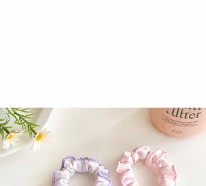Close-up of light purple and pink satin scrunchies with delicate overlock stitched edges