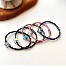 Close-up of five elastic hair ties with iridescent cube crystal beads in neutral tones
