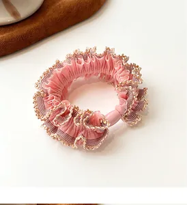 Detailed view of pink chiffon scrunchie with golden lurex edge and decorative bead