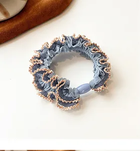 Detail of blue plaid elastic hair scrunchie with gold lace trim and decorative bead