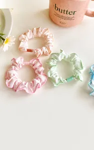 Close-up of floral hair scrunchies in pink, green and beige fabric with soft flower patterns