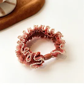 Close-up of red and white checkered scrunchie with lace edge and brown bead detail