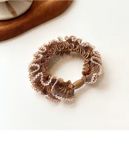 Close-up of brown ruffled scrunchie with wave lace edges and decorative resin bead