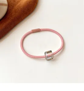 Detail of pink high-elastic hair tie with a clear faceted crystal square bead