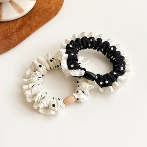 Set of two polka dot scrunchies in black and white with ruffled edges and buckles