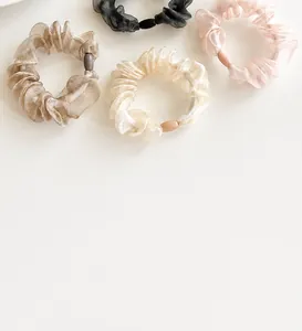 Detail of four organza scrunchies in black, pink, champagne and cream with resin buckles