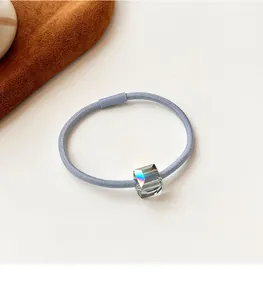 Detail of blue-grey elastic hair tie with faceted crystal cube and reinforced buckle