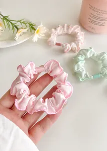 Close-up of pastel floral scrunchies with soft fabric texture and wavy edge detailing