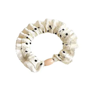 Minimalist beige polka dot hair scrunchie with a central decorative wooden bead