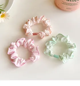 Detail of floral scrunchies set in pink and green with cherry patterns on soft fabric