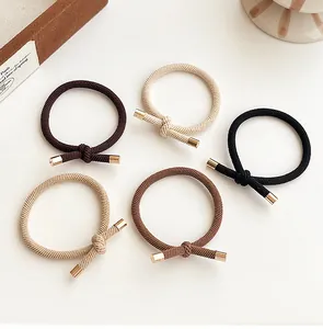Close-up of five earth-toned high elastic hair ties with gold metal knot accents