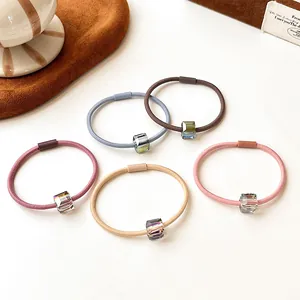 Five elastic crystal hair bands in muted colors with geometric pendants on white surface