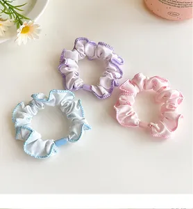 Detailed view of three pastel floral scrunchies with wavy edges and soft fabric texture