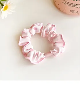 Detailed close-up of pink floral scrunchie with soft fabric texture and plastic clasp
