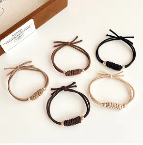 Détail de cinq élastiques à cheveux tissés avec perles métalliques et doubles nœuds