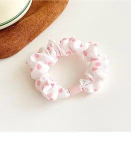 Detailed macro view of white fabric scrunchie with pink polka dots and pink plastic fastener