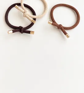 Close-up of high-elastic braided hair ties with gold metal clips in earth tones