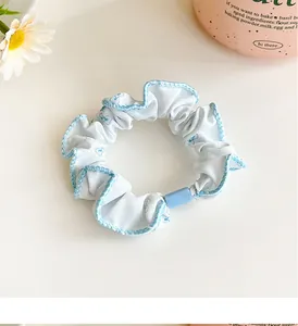 Detailed view of light blue hair scrunchie with bow patterns and blue cylinder buckle