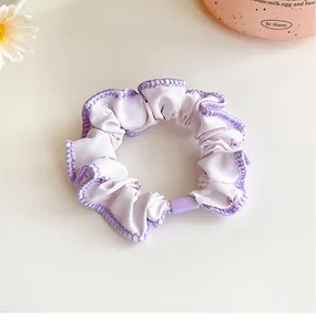 Close-up of lavender floral scrunchie with purple stitching on a creamy white desk