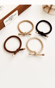 Close-up of four knotted elastic hair ties in neutral brown tones with metal clasps