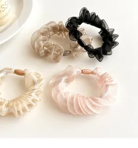 Detailed view of four organza scrunchies in black, champagne, beige and pink
