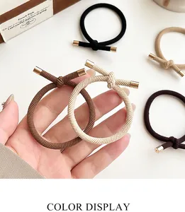 Detail showing elastic knotted hair ties with ribbed texture and gold metal accents