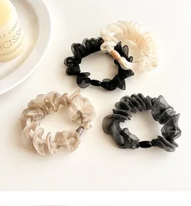 Detail of four organza scrunchies in black, white, champagne, and grey with bead accents