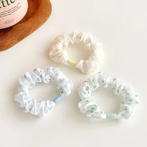 Three-piece set of polka dot scrunchies in yellow, blue, and green on white textured fabric