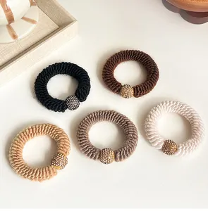 Detail of five earth-toned knitted hair ties with sparkling rhinestone-encrusted beads