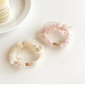 Detail of pleated organza hair scrunchies in champagne and pink with oval bead accents