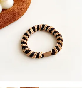 Detail van tweekleurig koffie en beige elastisch haarelastiekje met bruine gespsluiting