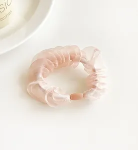 Detailed close-up of a pink organza scrunchie with soft pleats on a white surface