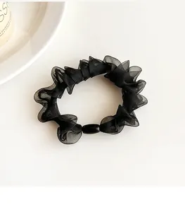 Detail of black organza scrunchie with layered pleats and a sleek decorative bead