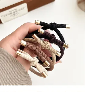 Detail of five elastic woven hair ties with elegant gold metal tips and knotted design