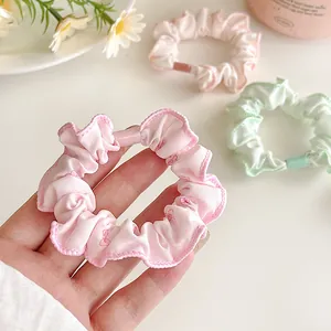 Three-piece floral scrunchie set including pink bow and pastel solid colors for hair