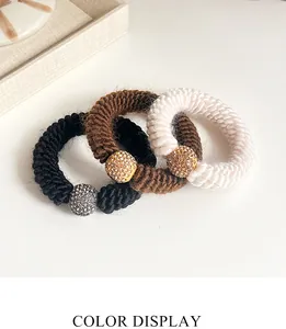 Detailed set of three knit hair ties in black, brown, and cream with rhinestone beads