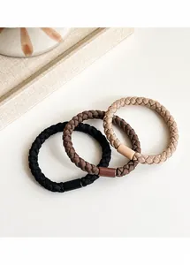 Close-up of three woven elastic hair ties in black, coffee, and beige on a tray