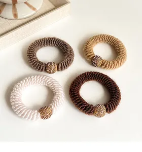 Detail view of four thick knitted hair ties in earth tones with crystal gold beads