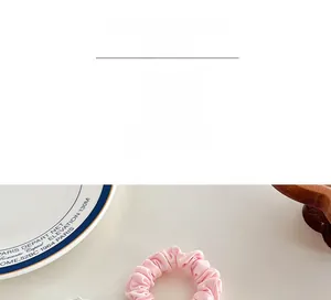 Detailed texture of pink and light green pleated fabric scrunchies with elastic band