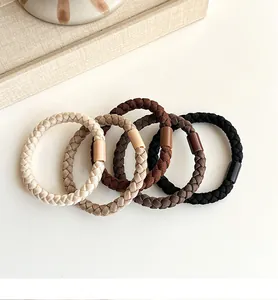 Detail of five woven high-elastic hair ties in earth-tone coffee shades on white surface
