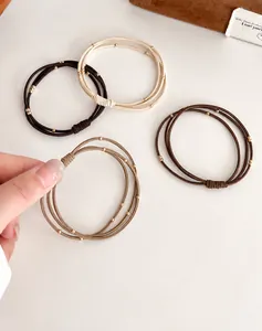 Détails de quatre élastiques à cheveux perlés aux tons neutres et perles dorées