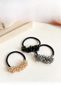 Detailed view of three crystal beaded elastic hair ties in black, silver and gold