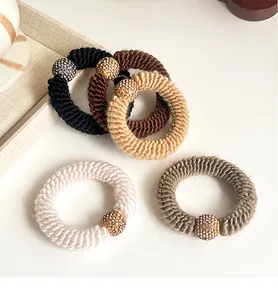 Detailed close-up of five chunky knitted hair ties with sparkling rhinestone beads