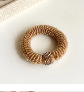 Detailed view of coffee-colored knitted hair tie featuring a sparkling rhinestone ball charm