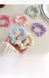 Close-up of colorful pleated fabric hair scrunchies on a minimalist white table setting