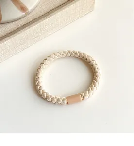 Detailed view of beige braided elastic hair tie with smooth cylindrical connector