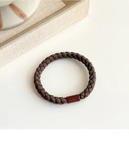 Close-up of brown woven elastic hair tie with a smooth plastic joint on a soft background