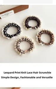 Detail of four leopard print knit hair scrunchies with white lace trimming and resin clasps
