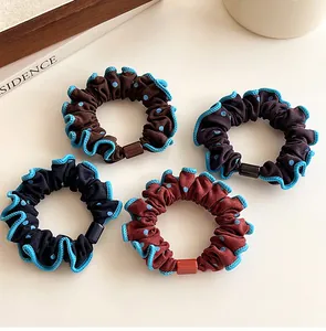 Detalle de cuatro coleteros de lunares con bordes ondulados azules y hebillas de resina