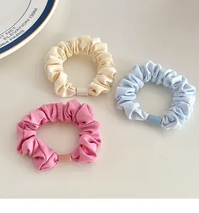 Close-up of three pastel fabric scrunchies with rectangular buckles on a clean desk